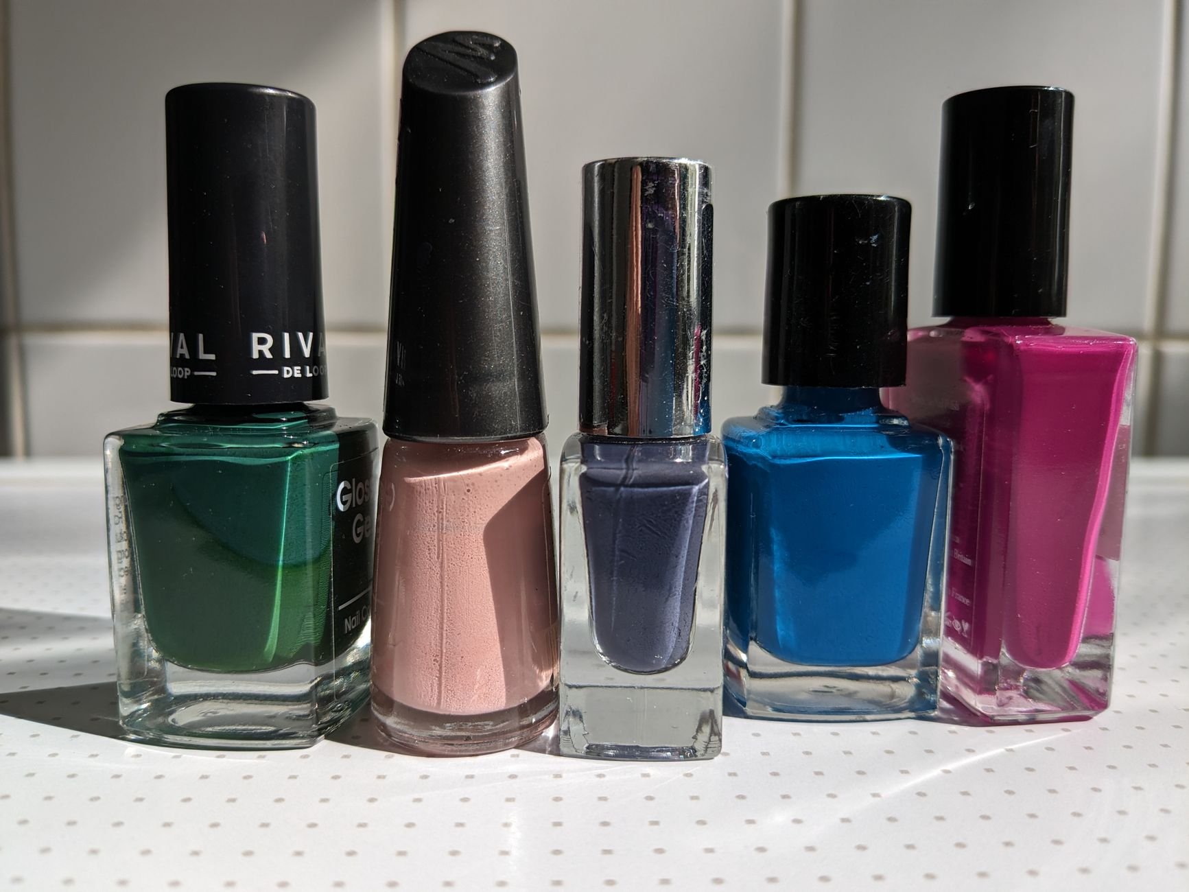 Five vibrant nail polish bottles arranged neatly on a light background.